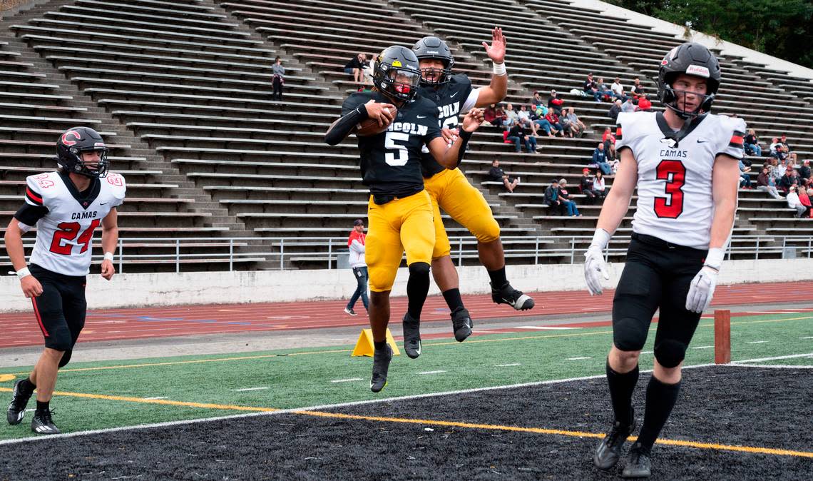 Lincoln quarterback Gabarri Johnson (5) and tight end Mikah Niuamoa celebrate Johnson’s touchdown run as Camas defenders Alex Holley and Bradley Prouse walk away during Saturday afternoon’s 4A football game at Lincoln Bowl in Tacoma, Washington, on Sept. 17, 2022. Lincoln won the game, 42-28.