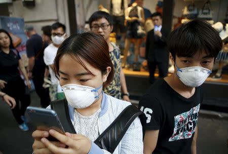 A woman wearing a mask to prevent contracting Middle East Respiratory Syndrome (MERS) uses her mobile phone in central Seoul, South Korea, June 15, 2015. REUTERS/Kim Hong-Ji