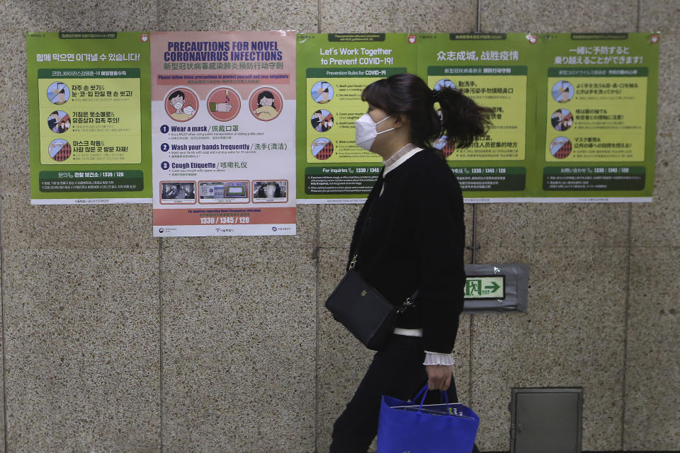 A woman wearing a face mask passes by posters about precautions against new coronavirus at a subway station in Seoul, South Korea, Saturday, March 21, 2020. For most people, the new coronavirus causes only mild or moderate symptoms, such as fever and cough. For some, especially older adults and people with existing health problems, it can cause more severe illness, including pneumonia. (AP Photo/Ahn Young-joon)