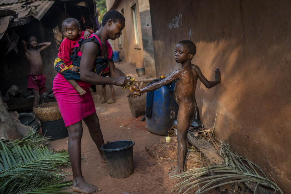 Anayo Mbah, 29, bathes her children in her home in Umuida, Nigeria, Saturday, Feb. 12, 2022. Mbah was in the final days of her sixth pregnancy when her husband, Jonas, fell ill with fever. By the time he was taken to a clinic, the motorcycle taxi driver was coughing up blood. He tested positive for COVID-19 and was still in the hospital when she gave birth days later. The baby would never meet her father. (AP Photo/Jerome Delay)