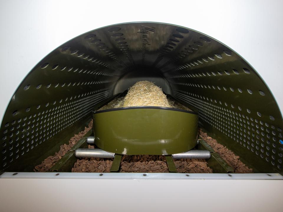 A body covered in organic materials is loaded into a circular pod.