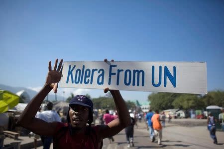 A protester holds up a sign during a demonstration against the UN mission in downtown Port-au-Prince November 18, 2010. REUTERS/Allison Shelley/File Photo