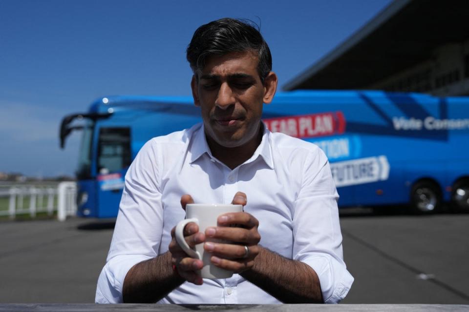 Britain's Prime Minister and Conservative Party leader Rishi Sunak holds a mug while speaking to journalists at Redcar racecourse (POOL/AFP via Getty)