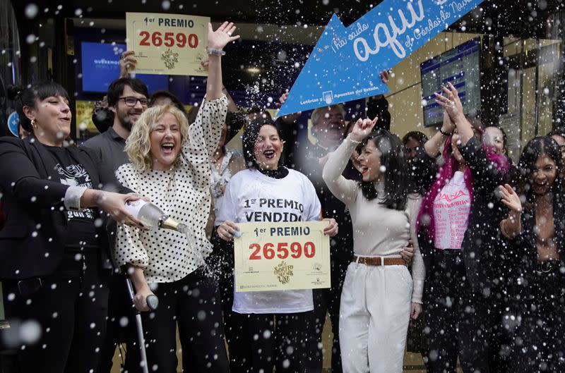 Los propietarios y empleados de la tienda "Dona Manolita" celebran la venta del número ganador del mayor premio de la lotería de Navidad "El Gordo" en Madrid