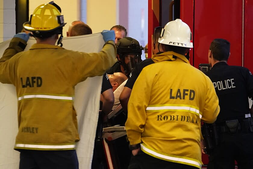 A man suspected of stabbing three people at Encino Hospital Medical Center is wheeled into an ambulance on Friday.