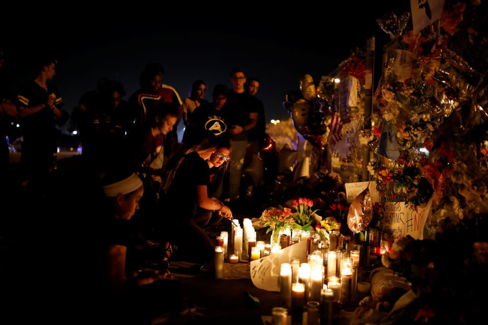 <p>People light candles in front of mementoes placed in front of the fence of the Marjory Stoneman Douglas High School to commemorate the victims of the mass shooting, in Parkland, Fla., Feb. 21, 2018. (Photo: Carlos Garcia Rawlins/Reuters) </p>