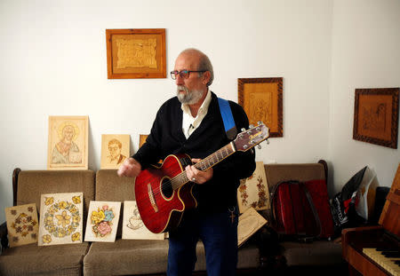 Christian artist and sculptor Naser Jeldha plays guitar in his studio in Gaza City December 4, 2016. REUTERS/Suhaib Salem