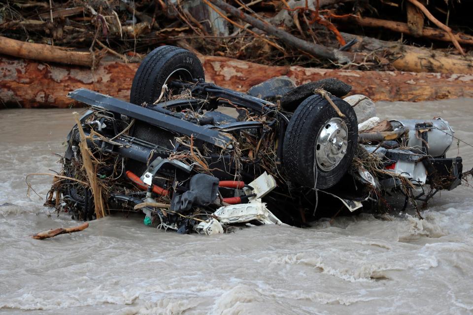 A destroyed car lies upside down in the riverbed following the flooding.