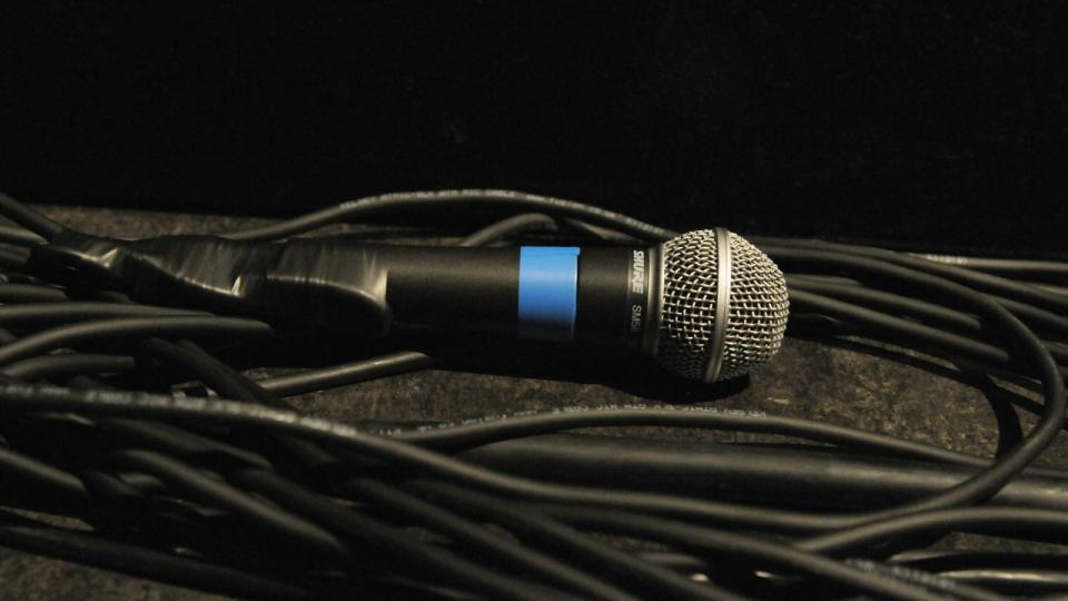 A Shure SM58 vocal microphone lying on top of an XLR cable