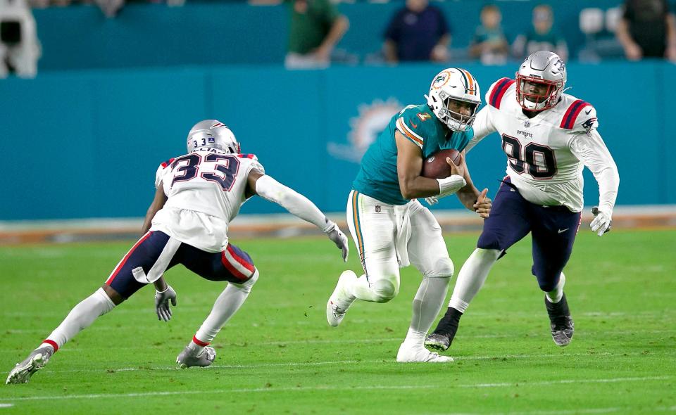 Miami Dolphins quarterback Tua Tagovailoa (1)runs through the New England Patriots defense for a first down late in the fourth quarter that wrapped up the game during NFL game at Hard Rock Stadium Sunday in Miami Gardens. 