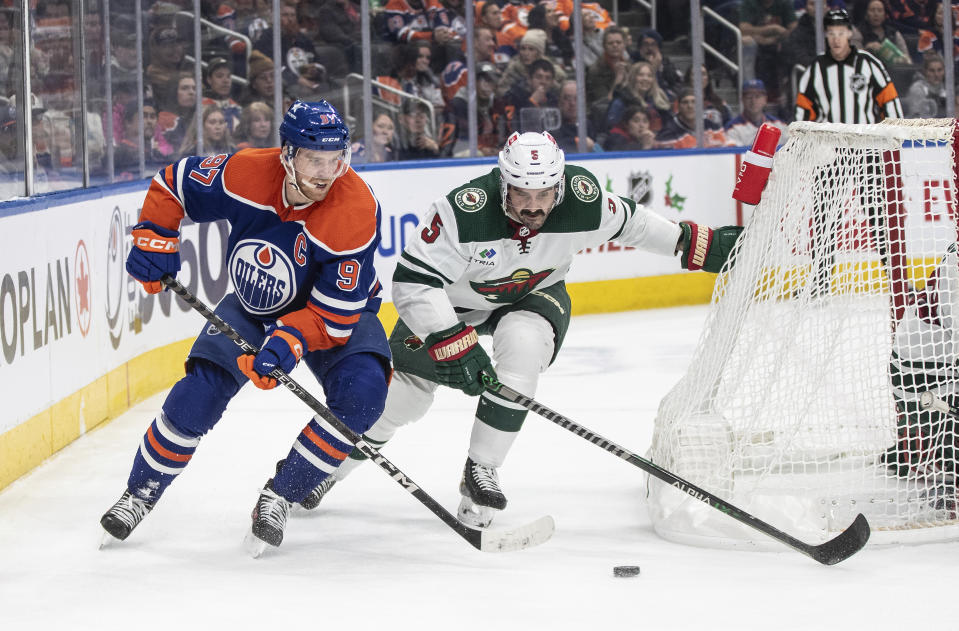 Minnesota Wild's Jacob Middleton (5) and Edmonton Oilers' Connor McDavid (97) vie for the puck during the second period of an NHL hockey game Friday, Dec. 8, 2023, in Edmonton, Alberta. (Jason Franson/The Canadian Press via AP)