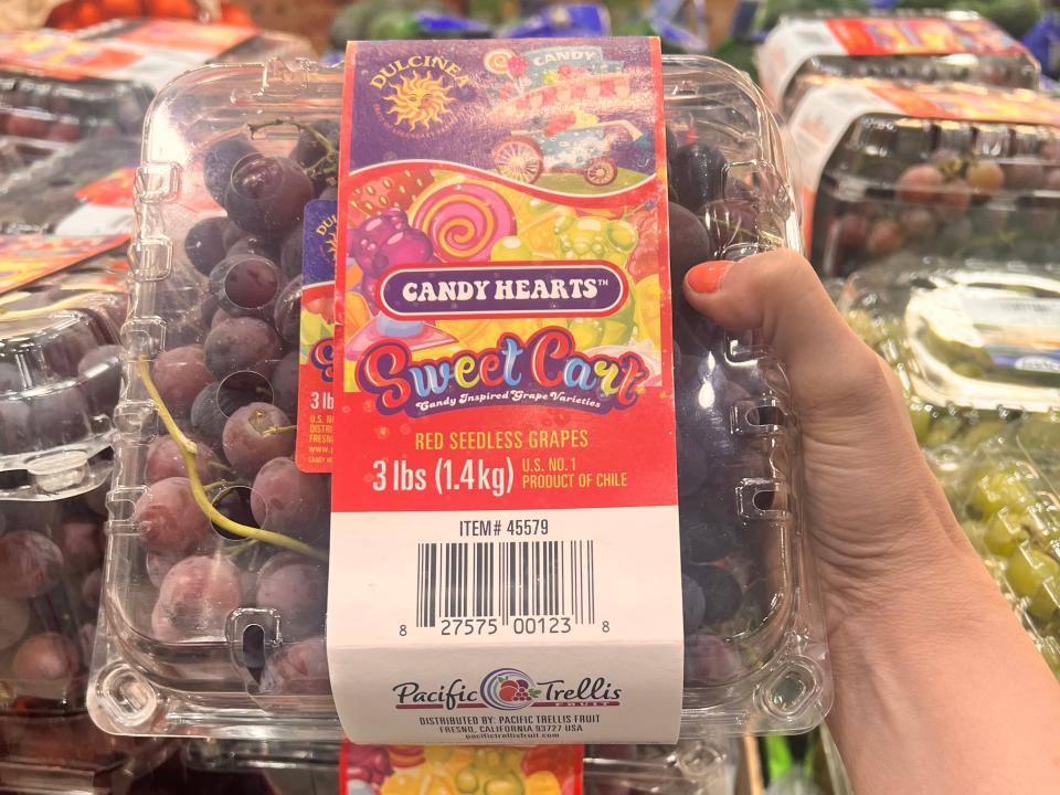 hand holding up a carton of red grapes at Costco