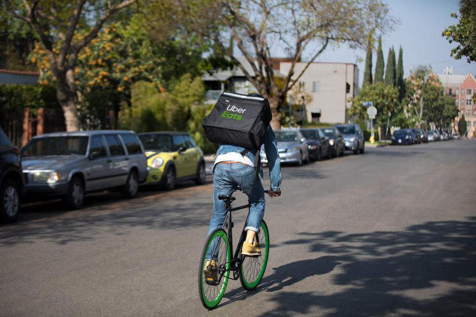 An Uber Eats courier makes a delivery by bike.