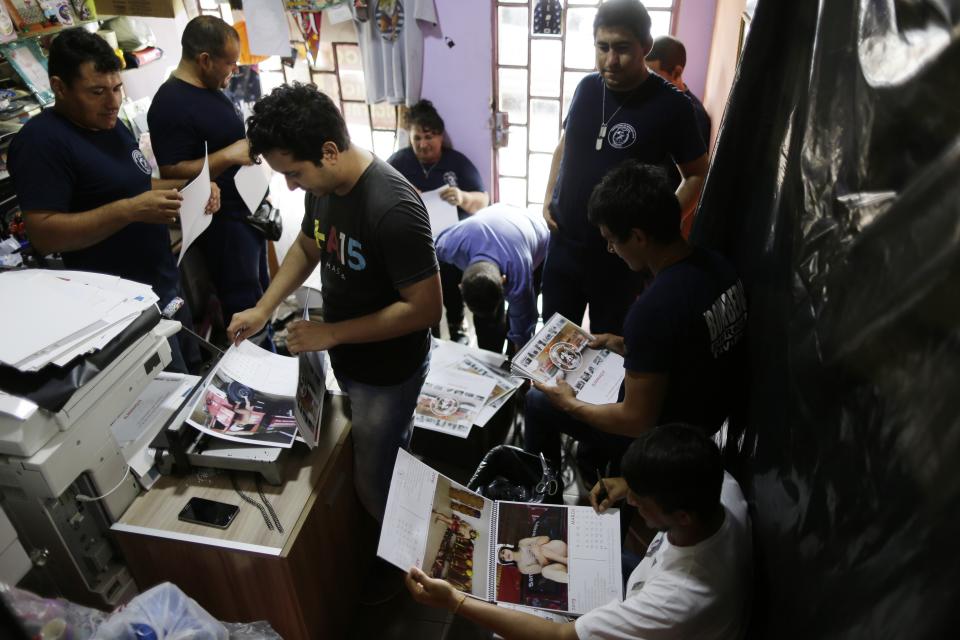 In this Jan. 12, 2019 photo, firefighters work putting calendars together in Asuncion, Paraguay. The San Roque Gonzalez fire station gets about $600 a month to serve the 16,000 residents of the town. But firefighters say that fuel and maintenance of the equipment, which includes an ambulance and a fire engine donated by Spain, costs about $1,000 a month. (AP Photo/Jorge Saenz)