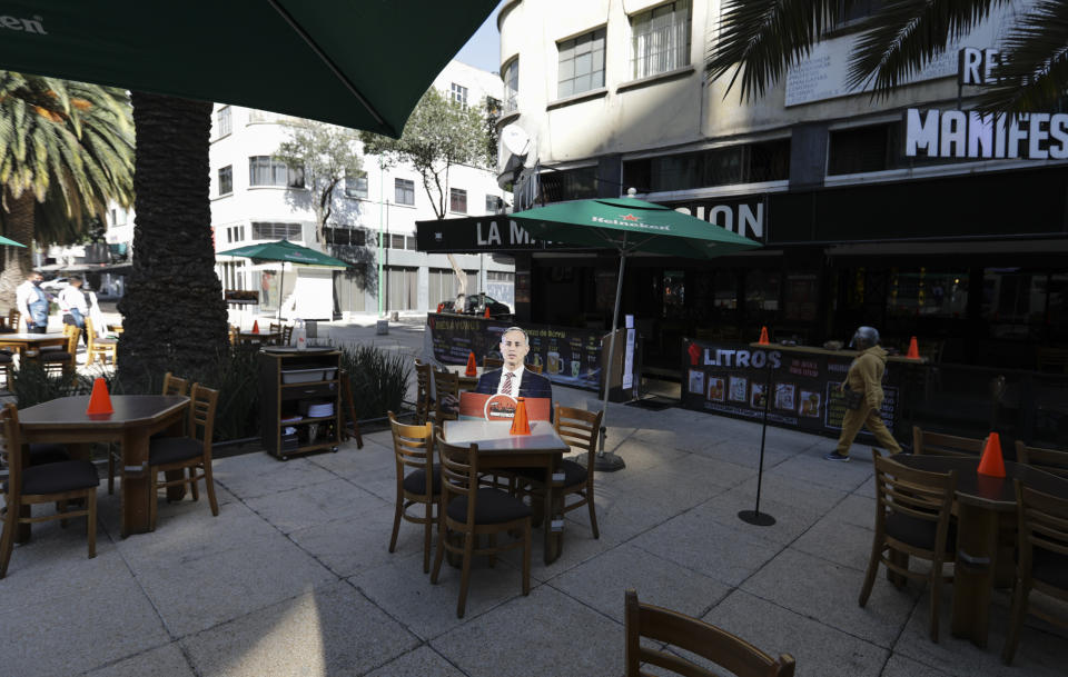 FILE - In this Feb. 4, 2021 file photo, a life-size cutout of Mexico's Deputy Health Secretary Hugo Lopez-Gatell is displayed on the patio of an outdoor restaurant in Mexico City, after the easing of restrictions related to the COVID-19 "red alert" shutdown, allowing eateries to serve diners in socially distanced, preferably outdoor spaces. As Mexico approaches 200,000 in officially test-confirmed deaths from COVID-19, the real death toll is probably higher due to the country’s extremely low rate of testing. (AP Photo/Eduardo Verdugo, File)