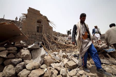 People stand on the rubble of houses destroyed by an air strike in the Okash village near Sanaa April 4, 2015. REUTERS/Mohamed al-Sayaghi