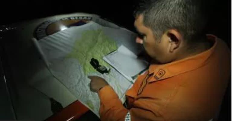Un miembro de Protección Civil marca un punto en un mapa donde pretenden iniciar un operativo de búsqueda de miembros de un grupo religioso que continúan desaparecidos en el estado Táchira