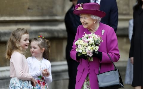 The Queen receives flowers from two girls after the service - Credit: AFP/TOLGA AKMEN 