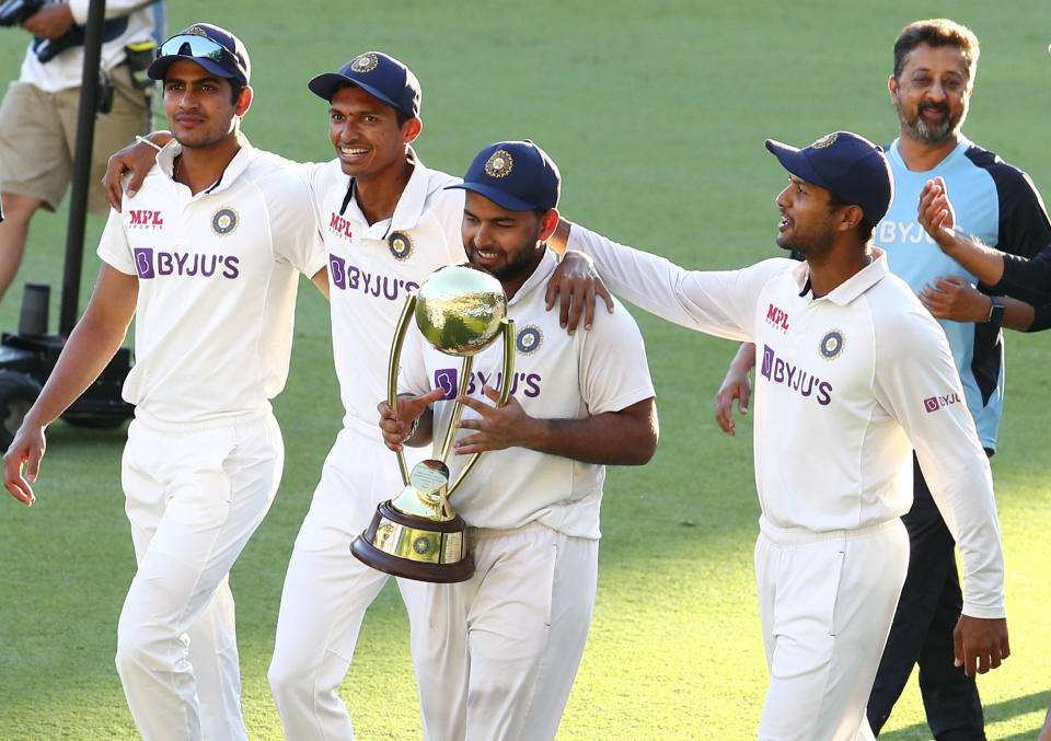 India's Rishabh Pant carries the trophy as he celebrates with his teammates after defeating Australia by three wickets on the final day of the fourth cricket test at the Gabba, Brisbane, Australia, Tuesday, Jan. 19, 2021.India won the four test series 2-1. (AP Photo/Tertius Pickard)