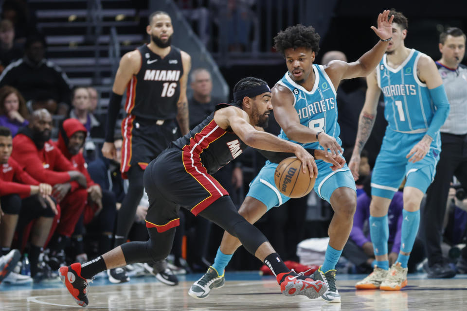 Miami Heat guard Gabe Vincent (2) keeps the ball from Charlotte Hornets guard Dennis Smith Jr. (8) during the first half of an NBA basketball game in Charlotte, N.C., Sunday, Jan. 29, 2023. (AP Photo/Nell Redmond)