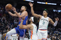 Golden State Warriors guard Stephen Curry, left, shoots against San Antonio Spurs guard Derrick White, bottom, and forward Keldon Johnson (3) during the second half of an NBA basketball game in San Francisco, Saturday, Dec. 4, 2021. (AP Photo/Jeff Chiu)