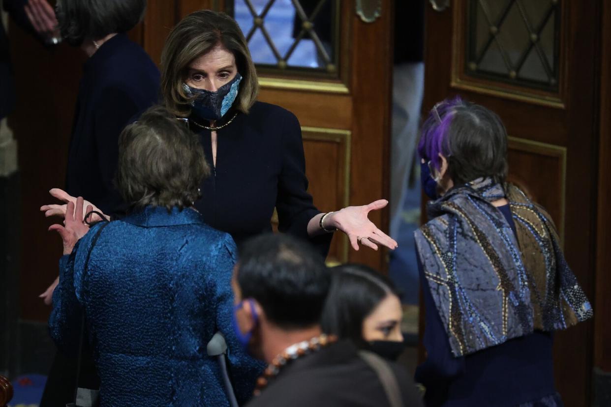 Nancy Pelosi talks with House members in the chamber.