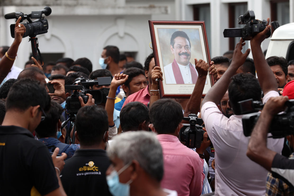 A portrait of Prime Minister Mahinda Rajapaksa is held by a protester in a pink shirt.