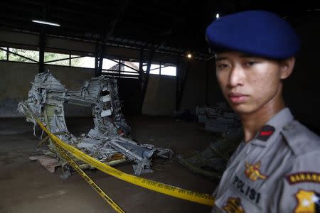 A police officer stands near part of the fuselage of crashed AirAsia Flight QZ8501 inside a storage facility at Kumai port in Pangkalan Bun, January 19, 2015. REUTERS/Beawiharta