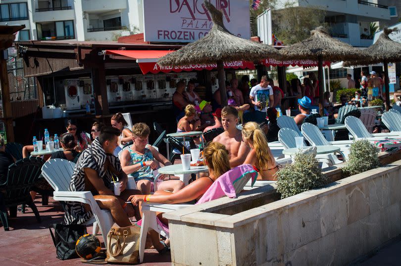 Tourist enjoy drinks at a bar terrace at Magaluf beach.