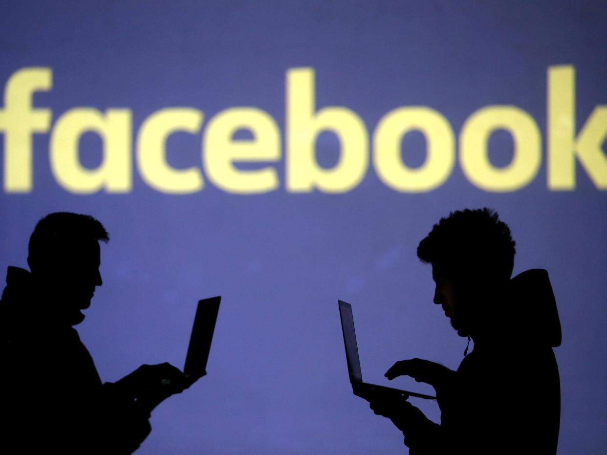 FILE PHOTO: Silhouettes of laptop users are seen next to a screen projection of Facebook logo in this picture illustration taken March 28, 2018.  REUTERS/Dado Ruvic/Illustration