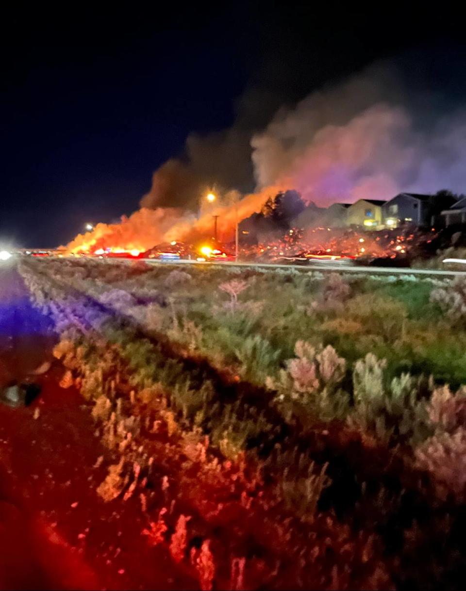 A wildfire threatened homes after starting in spots along nearly a mile of Interstate 182 in south Richland Saturday night.