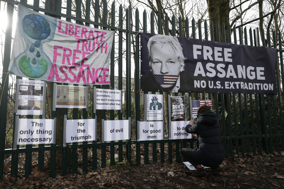 A supporter of Julian Assange tapes up protest messages on a fence on the second day of a week of opening arguments for the extradition of Wikileaks founder Julian Assange outside Belmarsh Magistrates' Court in south east London, Tuesday, Feb. 25, 2020. U.S. authorities, want to try Assange on espionage charges. A lawyer for the Americans said the Australian computer expert was an “ordinary” criminal whose publication of hundreds of thousands of secret military documents put many people at risk of torture and death. (AP Photo/Matt Dunham)