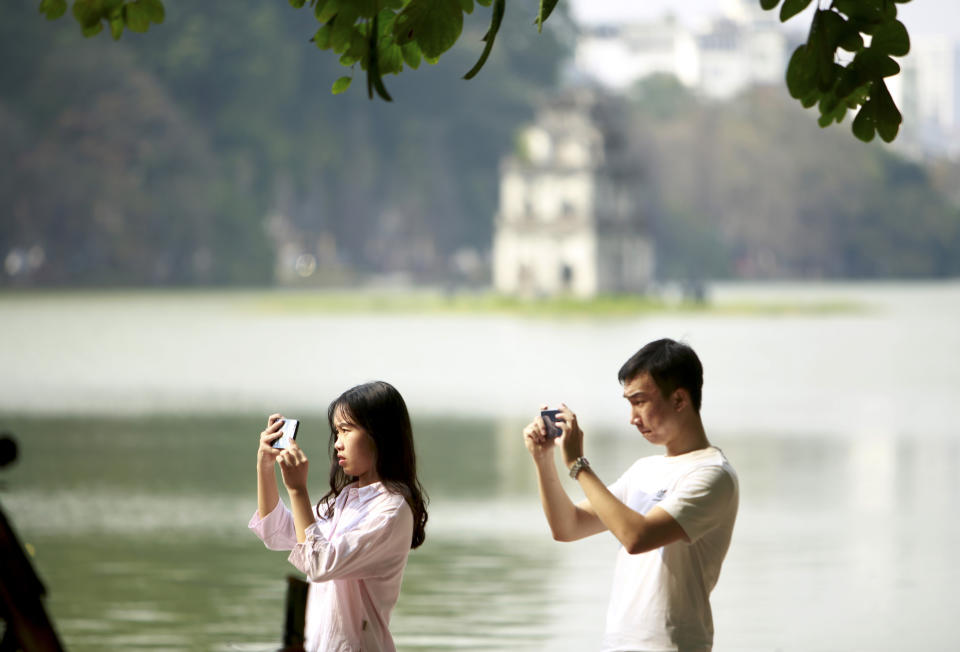 In this Feb. 21, 2019, photo, a couple take photos at the Hoan Kiem lake in Hanoi, Vietnam. The Vietnamese capital once trembled as waves of American bombers unleashed their payloads, but when Kim Jong Un arrives here for his summit with President Donald Trump he won’t find rancor toward a former enemy. Instead, the North Korean leader will get a glimpse at the potential rewards of reconciliation. (AP Photo/Hau Dinh)