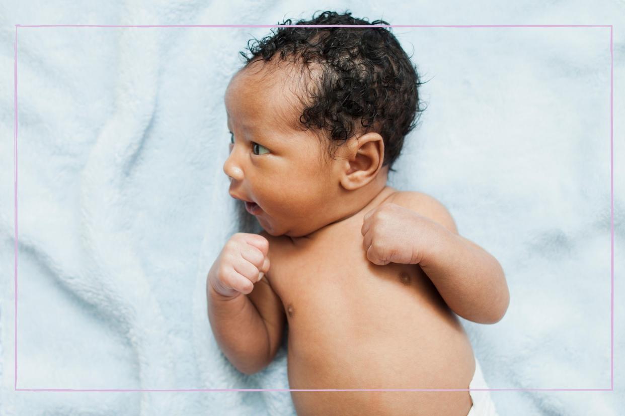  A newborn baby lying on a pale blue blanket. 