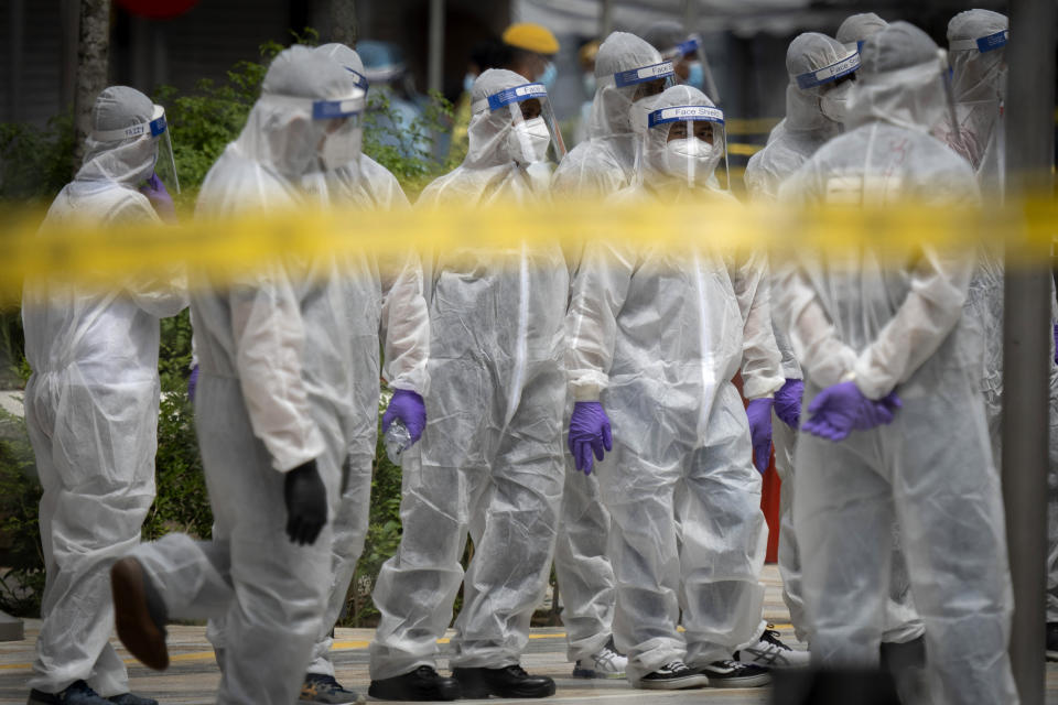 Immigration officers wearing full protection suits prepare at a coronavirus locked down area in Kuala Lumpur, Malaysia, on Sunday, May 3, 2020. Malaysian Prime Minister Muhyiddin Yassin says the economy needs to be revived as billions have been lost during the partial lockdown that began in March. (AP Photo/Vincent Thian)