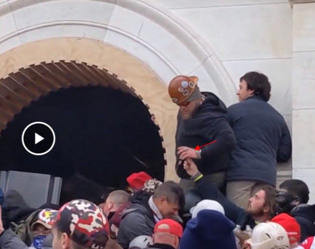 James Mault, pictured in the red hard hat, is shown holding a pepper spray canister that he sprayed at police officers in the western tunnel at the U.S. Capitol on Jan. 6, prosecutors said.