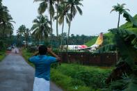 A man takes pictures with his mobile phone near the wreckage of an Air India Express jet at Calicut International Airport in Karipur, Kerala, on August 8, 2020. - Fierce rain and winds lashed a plane carrying 190 people before it crash-landed and tore in two at an airport in southern India, killing at least 19 people and injuring scores more, officials said on August 8. (Photo by Arunchandra BOSE / AFP) (Photo by ARUNCHANDRA BOSE/AFP via Getty Images)