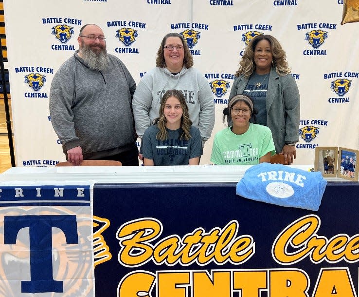 Battle Creek Central's Tia Henry, sitting at right, and Jadyn Horne, sitting at left, each committed to play college volleyball at Division III Trine University during a signing ceremony at BCC High School.