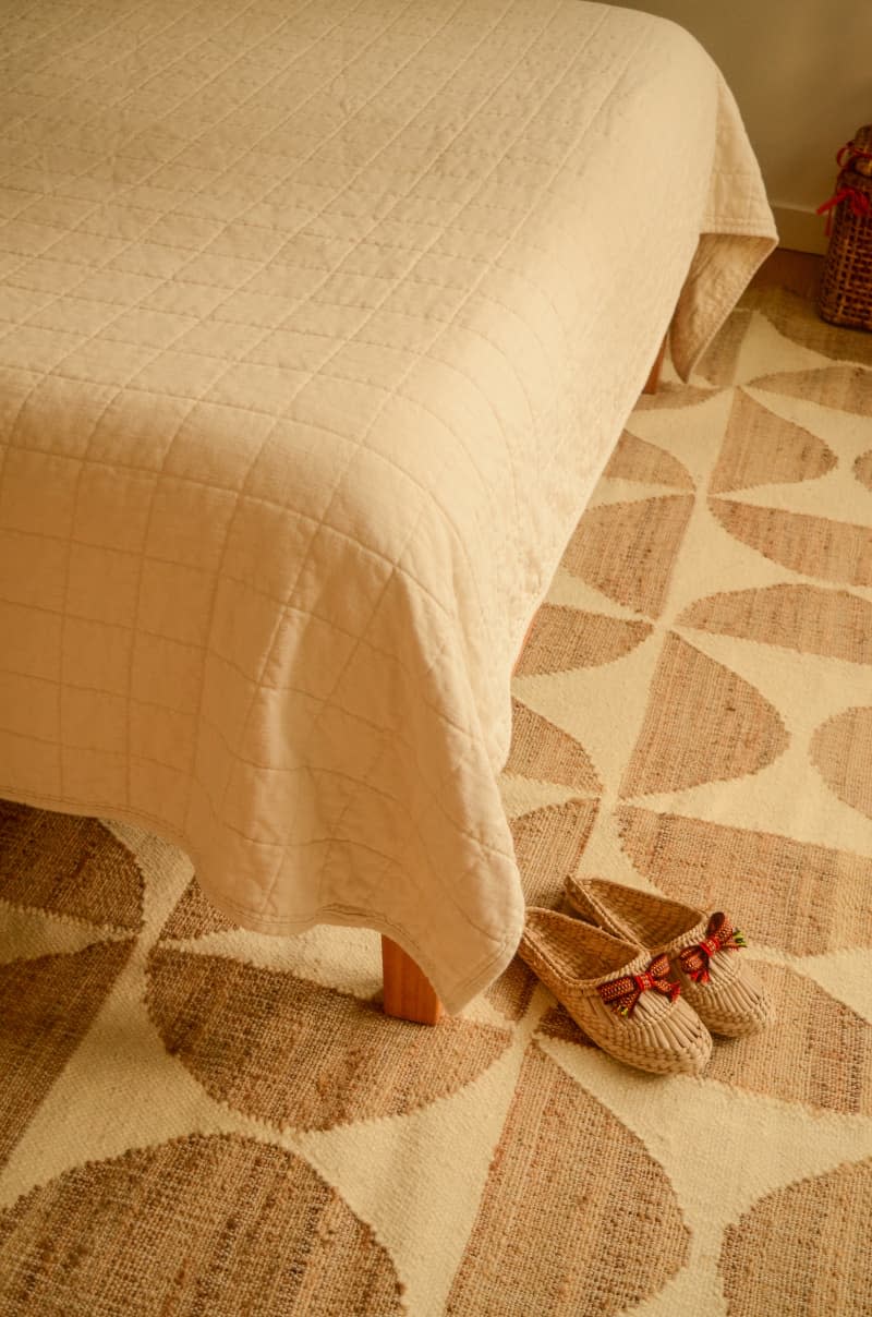Slippers on graphic rug of neutral bedroom.