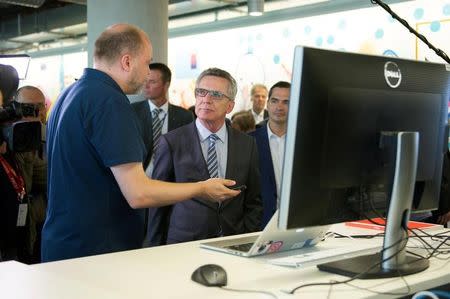 German Interior Minister Thomas de Maiziere talks to an employee during a vistit at the Facebook office in Berlin, Germany August 29, 2016. REUTERS/Stefanie Loos