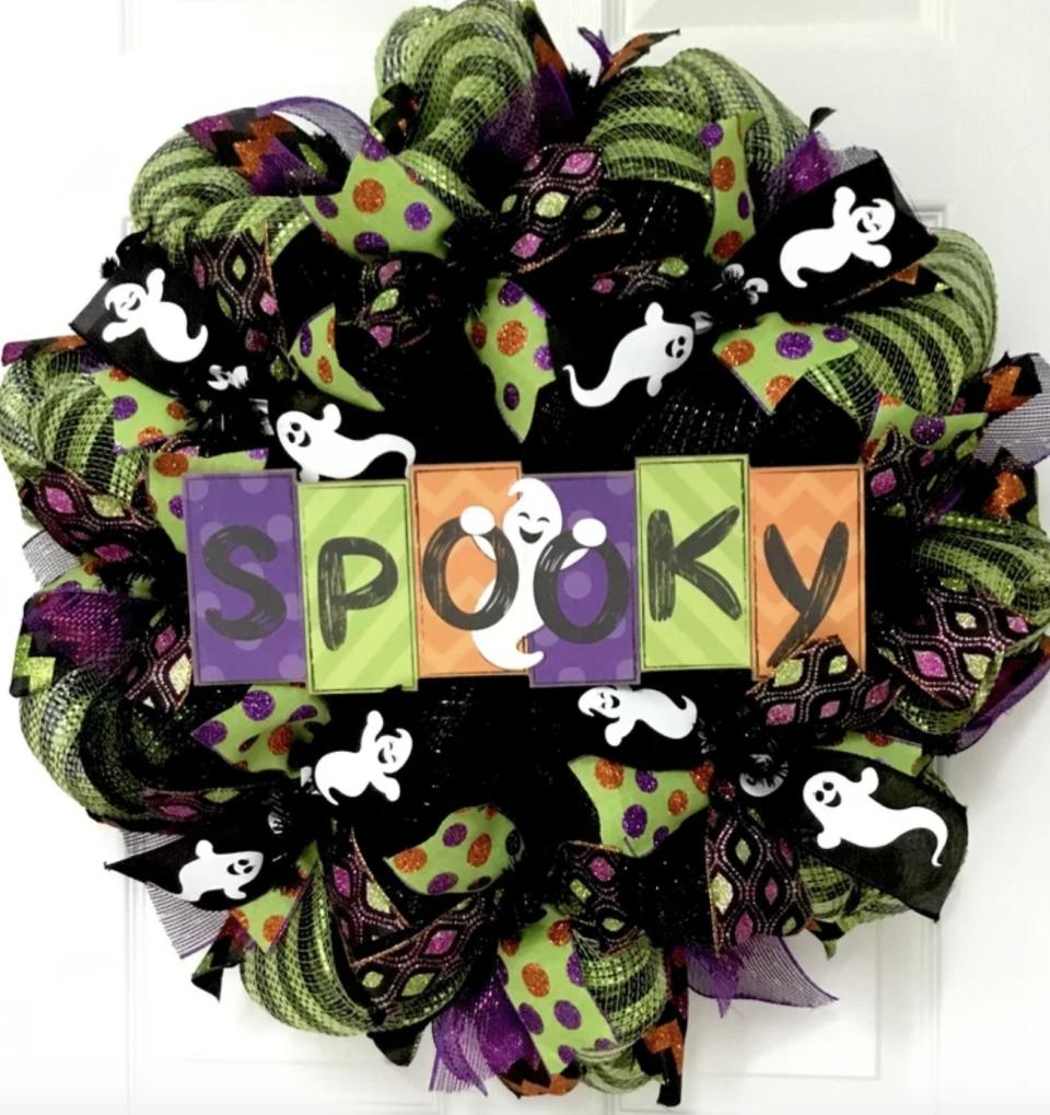 The mesh green purple and orange wreath has sparkles, ghosts, stripes, polka dots and a sign that says "SPOOKY"