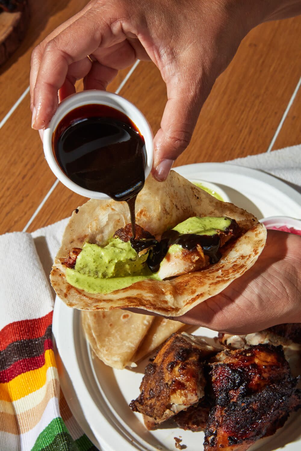 Rotisserie jeera Chicken being assembled into tacos with mole, GG sauce and handmade tortillas