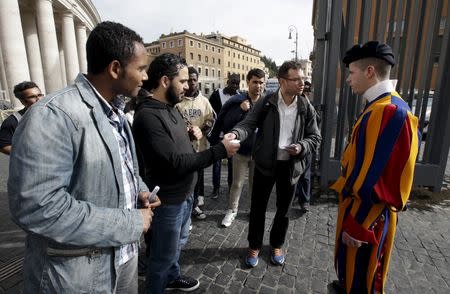 A volunteer (2nd R) and some homeless people talk with a Swiss guard before entering the Vatican March 26, 2015. REUTERS/Max Rossi