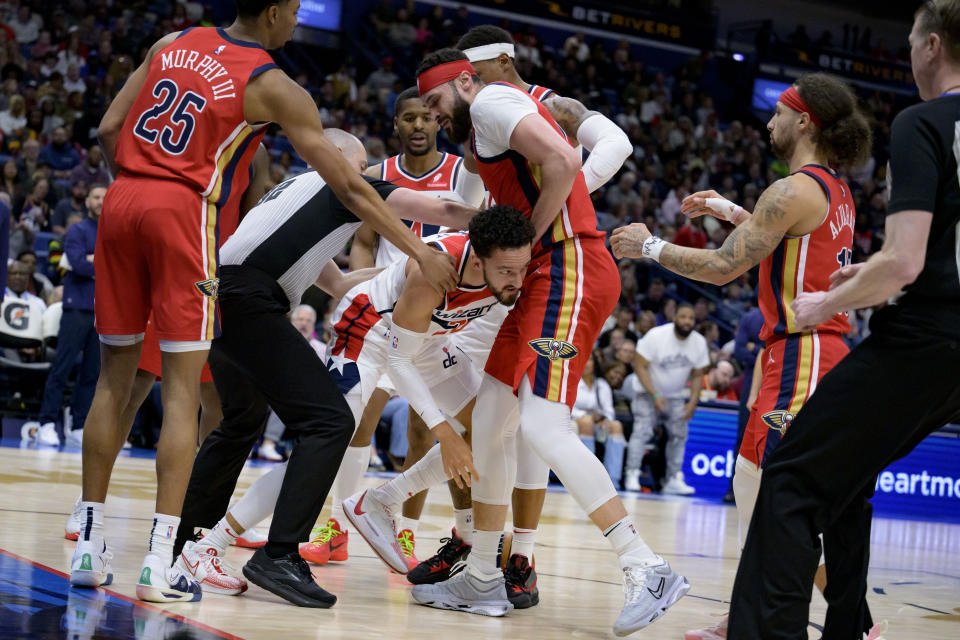 Washington Wizards guard Landry Shamet, bottom center, pushes into New Orleans Pelicans forward Larry Nance Jr., top, after they battled for a rebound that resulted in a jump ball and offsetting fouls on Nance and Shamet during the second half of an NBA basketball game in New Orleans, Wednesday, Feb. 14, 2024. (AP Photo/Matthew Hinton)