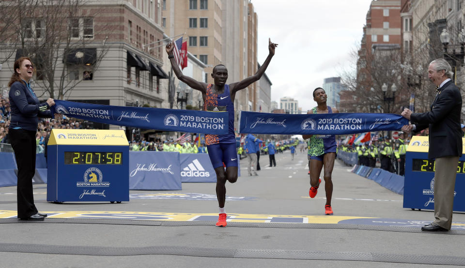 FILE - Lawrence Cherono, of Kenya, breaks the tape to win the 123rd Boston Marathon in front of Lelisa Desisa, of Ethiopia, right, on Monday, April 15, 2019, in Boston. Cherono, a Kenyan runner who won the Boston and Chicago marathons has been banned for seven years for doping and trying to use fake documents to explain his failed drug test, the Athletics Integrity Unit said Wednesday July 10, 2024. (AP Photo/Winslow Townson, File)