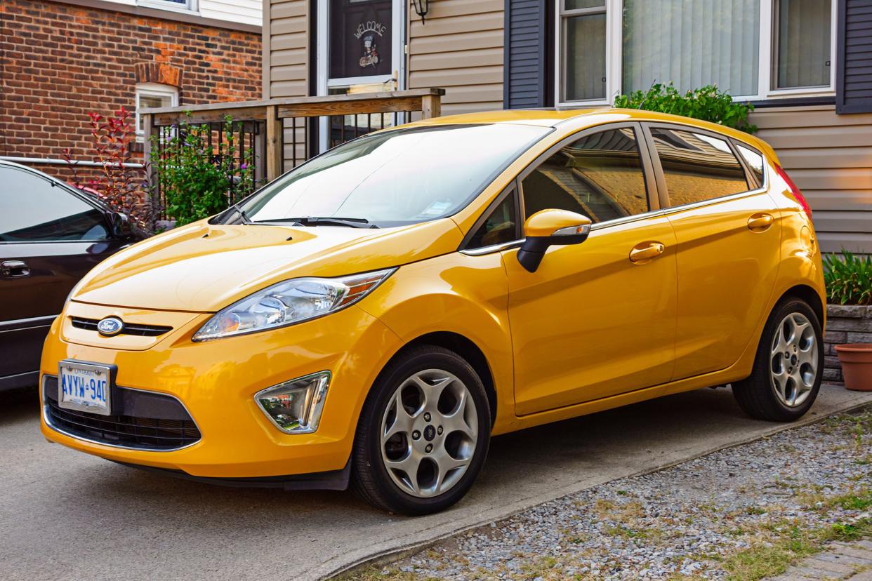 orange-yellow colored Ford Fiesta hatchback parked on a driveway