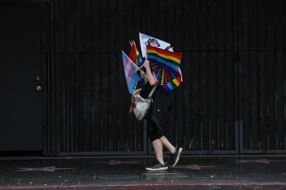 A vendor selling different colored flags heads up Hollywood Boulevard before the 2024 LA Pride Parade.