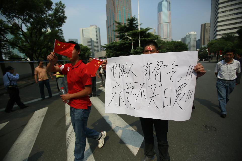 A small group of Chinese protesters march with national flags and an anti-Japan banner that reads "Chinese have guts, won’t buy Japanese goods forever." in front of the Japanese Consulate General in Shanghai, China, Wednesday Sept. 19, 2012. (AP Photo/Eugene Hoshiko)