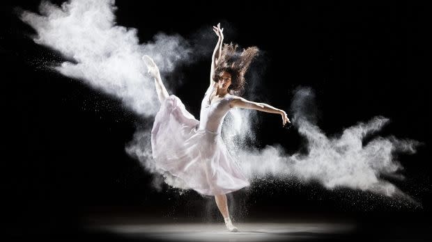 Ballerina performing in white powder in a dark room