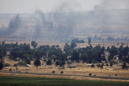 Smoke rises as a loaded bus drives near Quneitra at the Syrian side of the Israeli Syrian border as it is seen from the Israeli-occupied Golan Heights, Israel July 22, 2018. REUTERS/Ronen Zvulun